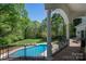 Inviting outdoor pool and manicured lawn, viewed from a covered patio with elegant columns and stone flooring at 7912 Baltusrol Ln, Charlotte, NC 28210