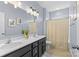 Bright bathroom with a double vanity, framed mirrors, and a shower with patterned curtain at 8429 Golden Stone Ln, Fort Mill, SC 29707