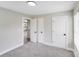 This is a bedroom with neutral walls and carpeted floors, two doors with black hardware, and a view of a kitchen at 11 Cobblestone Nw Ln, Concord, NC 28027