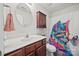 Bright bathroom with brown vanity, white counter, round mirror, and colorful shower curtain at 117 S Canyon Ridge S Dr, Mount Holly, NC 28120