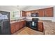 Traditional kitchen features brown cabinetry, light countertops, and black appliances at 117 S Canyon Ridge S Dr, Mount Holly, NC 28120