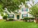Inviting home with green door and shutters, complemented by lush lawn and mature landscaping. For Sale by Canopy2025 at 11719 Withers Mill Dr, Charlotte, NC 28278