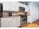 Kitchen featuring stainless steel range, microwave, and white cabinetry against hardwood floors at 13216 Old Compton Ct, Pineville, NC 28134