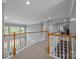 A large loft area with staircase and balustrade overlooking the floor below, featuring built-in bookshelves at 18305 Dembridge Dr, Davidson, NC 28036
