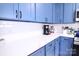 Close-up of white countertops and backsplash, with stainless steel appliances, and blue cabinets for a modern look at 201 Mitchell St, Belmont, NC 28012