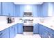 A modern kitchen featuring stainless steel appliances, blue cabinets, white subway tile backsplash, and quartz countertops at 201 Mitchell St, Belmont, NC 28012