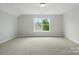 A spacious bedroom with neutral carpet and trim, featuring a single window with wooded views at 2020 Embassy Ct # 48, Charlotte, NC 28213