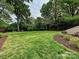 Spacious backyard featuring lush green grass, mature trees, and mulched flowerbeds at 2417 Calais Pl, Charlotte, NC 28211