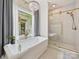 Bright bathroom featuring a chandelier over the soaking tub, a glass enclosed shower, and patterned tile flooring at 2417 Calais Pl, Charlotte, NC 28211