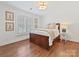 Comfortable bedroom featuring hardwood floors, neutral walls, one window, and a cozy, wooden bed frame at 2417 Calais Pl, Charlotte, NC 28211