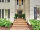 Close-up of a house entrance featuring a black front door, brick steps, and manicured landscaping at 2417 Calais Pl, Charlotte, NC 28211