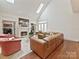 Living room featuring a fireplace, hardwood floors, skylights, large windows, and leather sectional couch at 2417 Calais Pl, Charlotte, NC 28211