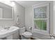 Bright half bathroom with pedestal sink, decorative mirror, and plantation shutters at 2418 Ainsdale Rd, Charlotte, NC 28226