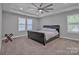 Spacious bedroom featuring a tray ceiling, ceiling fan, and ample natural light from the windows at 3075 Jamestown Dr, Gastonia, NC 28054