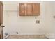 Functional laundry room with overhead storage and tile floor at 317 Port Royal Dr, Matthews, NC 28105