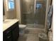 Bathroom featuring shower with gray tile, glass doors, and dark wood vanity at 3173 Pinehills Way, Mount Holly, NC 28120
