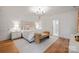 This bedroom features natural light, an elegant chandelier, and a bench at the foot of the bed at 3300 Sharon Rd, Charlotte, NC 28211