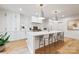 Bright kitchen boasts white cabinets, pendant lights, large island, and hardwood floors at 3300 Sharon Rd, Charlotte, NC 28211