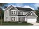 Two-story home with gray siding, stone accents, an attached garage, and a manicured lawn and landscaping at 404 Balboa St, Matthews, NC 28104