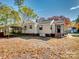 The backyard shows the house and carport near a yard with mature trees and blue skies at 412 Keels Ave, Rock Hill, SC 29730