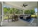 Spacious screened porch featuring a ceiling fan, dining table, and a comfortable seating area with forest views at 424 Balboa St, Matthews, NC 28104