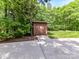Outdoor storage shed on a concrete path surrounded by lush greenery and mature trees at 4301 Middle Stream Rd, Charlotte, NC 28213