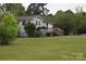 Home with a cozy exterior, featuring a small porch and set in a lush, grassy yard with surrounding trees at 4671 Lucas Ct, Harrisburg, NC 28075