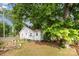Back exterior view of the home showing the yard, mature trees, and gardening area at 506 Englewood Ne St, Concord, NC 28025