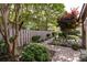 Landscaped backyard featuring a stone walkway, bench, mature trees, and lush plantings at 5128 Dunes Ct, Charlotte, NC 28226