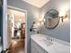 Well-lit bathroom with a vanity with a round mirror, sconces, and view through the doorway at 5128 Dunes Ct, Charlotte, NC 28226