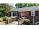 Quaint brick home with a bright red door and accessible ramp, surrounded by manicured landscaping at 536 Hartness Rd, Statesville, NC 28677