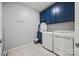 Bright laundry room featuring blue cabinets, tiled floor, and modern washer and dryer at 536 Rustlewood Way, Rock Hill, SC 29732