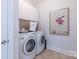 Bright laundry room with white cabinets, washer, dryer, and flamingo artwork at 6231 Wakehurst Rd, Charlotte, NC 28226