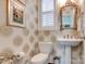 Chic powder room featuring patterned wallpaper, a pedestal sink, and elegant fixtures at 6231 Wakehurst Rd, Charlotte, NC 28226