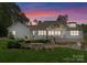 A white home features a backyard with a deck, green grass, and a table and chairs under a red and pink sky at 7351 Bay Cove Ct, Denver, NC 28037