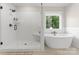 Bathroom featuring a luxurious soaking tub, glass-enclosed shower, tiled walls and a window with a view at 7351 Bay Cove Ct, Denver, NC 28037