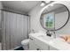 Clean bathroom with white vanity, round mirror, striped shower curtain, and natural light, creating a calming space at 7351 Bay Cove Ct, Denver, NC 28037