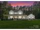Charming two-story white farmhouse with a spacious front yard and inviting porch at dusk at 7351 Bay Cove Ct, Denver, NC 28037