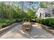 Stone patio with outdoor dining area surrounded by lush landscaping and mature trees at 7351 Bay Cove Ct, Denver, NC 28037