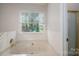 Soaking tub features tile surround, a window for natural light, and gold fixtures at 741 Bermuda Ave, Gastonia, NC 28054