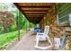 Covered patio with a brick exterior and a peaceful outdoor seating area overlooking the green landscape at 910 Surry Dr, Shelby, NC 28152