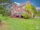 Expansive backyard featuring a wooden deck, lush lawn, and mature trees at 914 Olive Mill Ln, Matthews, NC 28104