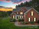 Charming two-story brick home featuring manicured landscaping and inviting front porch at sunset at 914 Olive Mill Ln, Matthews, NC 28104