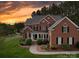 Charming two-story brick home featuring manicured landscaping and inviting front porch at sunset at 914 Olive Mill Ln, Matthews, NC 28104