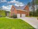 View of the brick house highlighting the three-car garage and lush green lawn at 914 Olive Mill Ln, Matthews, NC 28104