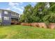 Large backyard with a wooden fence, well manicured grass and mature trees at 933 Tennyson Dr, Charlotte, NC 28208