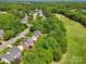 Aerial view of houses nestled in a lush green area with a golf course, showcasing a beautiful community setting and recreational opportunities at 10716 Persimmon Creek Dr, Mint Hill, NC 28227