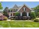Charming brick home with a covered front porch, lush landscaping, and a well-manicured lawn at 10716 Persimmon Creek Dr, Mint Hill, NC 28227