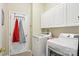 Convenient laundry room with modern washer, dryer, and storage cabinets, plus a door with coat rack at 10716 Persimmon Creek Dr, Mint Hill, NC 28227