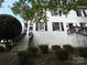 View of the front of the house with dark shutters and white brick, surrounded by greenery at 119 N Laurel Ave # 1, Charlotte, NC 28207